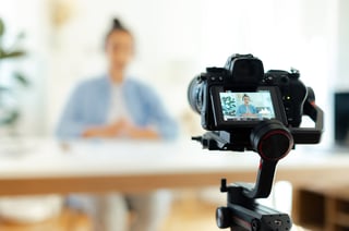 Young woman blogger sitting at a desk looking at camera, recording education tutorial vlog for social media