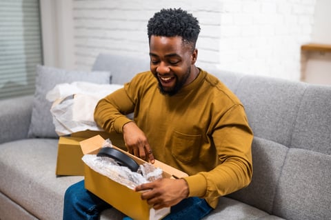 Joyful African-American man opens a box with curiosity and excitement